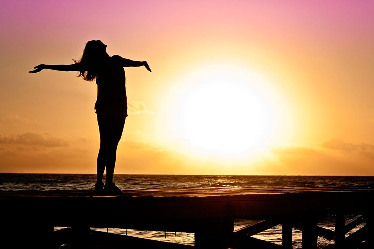 mujer feliz en el atardecer en un muelle