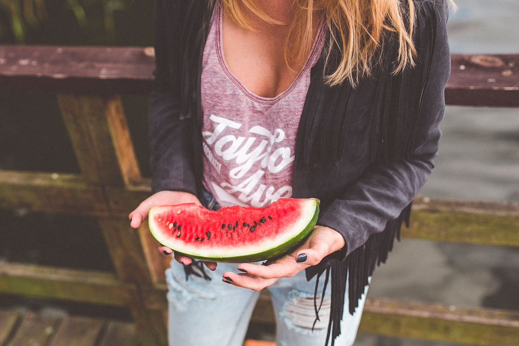 mujer sosteniendo un pedazo de sandia