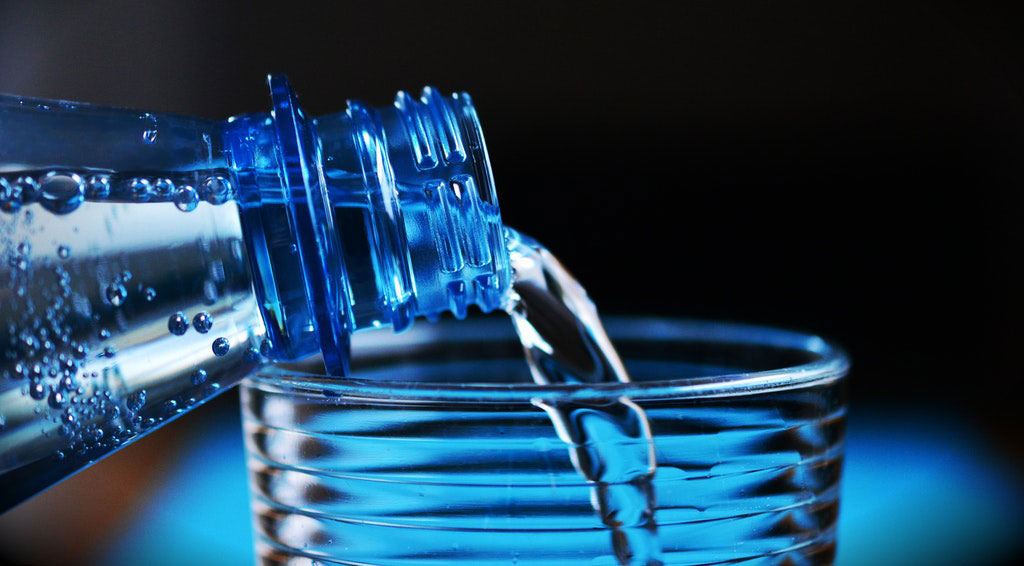 vaso de vidrio siendo llenada con agua mineral para obtener más energía