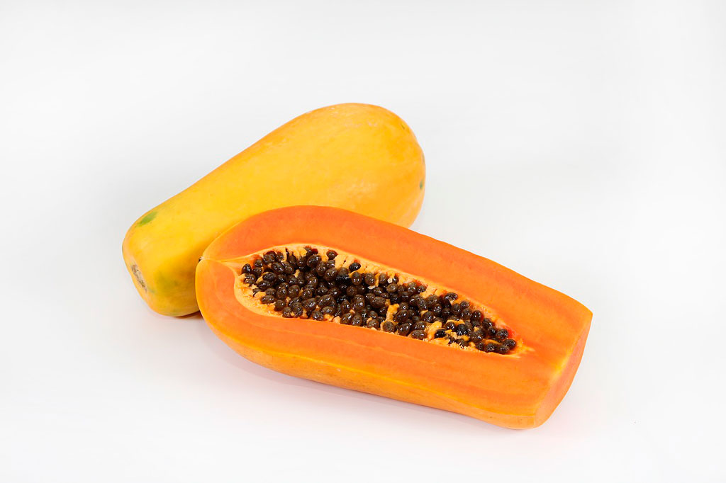 vitamina c aportada por papaya encima de una mesa blanca